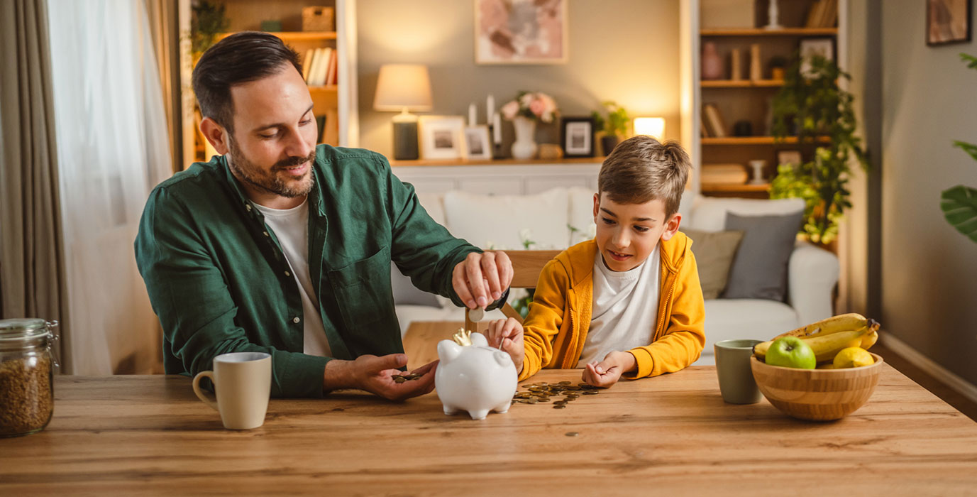Father and son putting coins in piggy bank