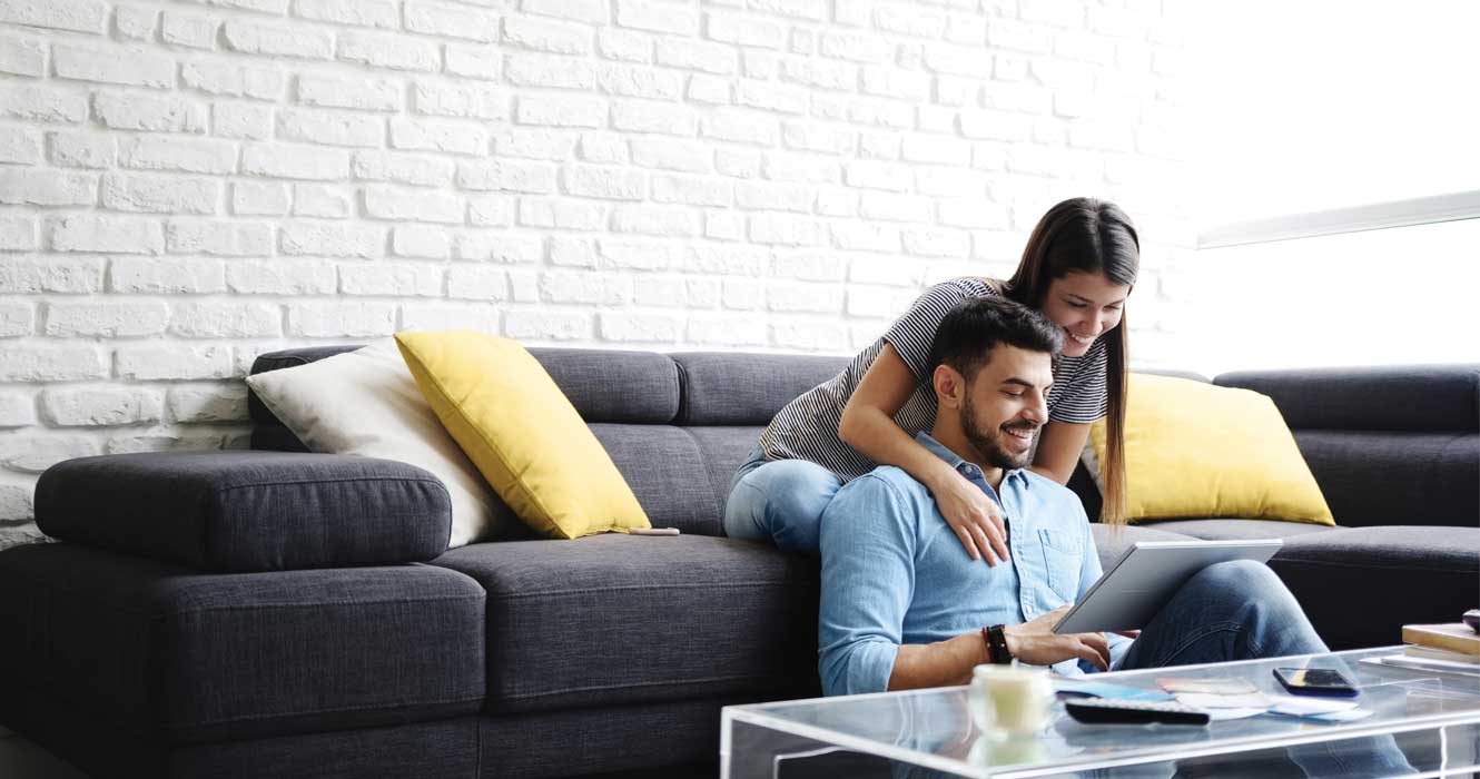 Couple on a sofa looking at an online application.