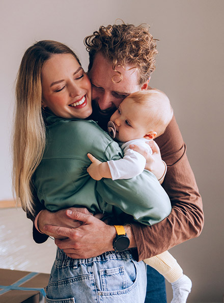 Young family holding baby in living room